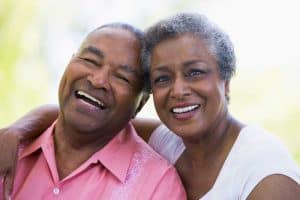 middle aged man and woman sitting close together smiling with womans arm around man