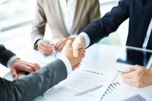 close up of two hands shaking with business suits on