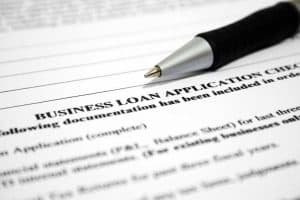 close up of a business loan application with a pen sitting on top of the paper