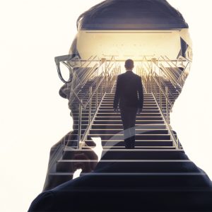 close up on the side of a man thinking with a man walking up stairs in the silhouette of the side profiled man