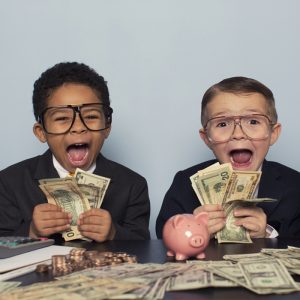 two little boys dressed in buisness suits with money all around them with an excited expression